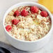 A bowl of oatmeal topped with raspberries and sliced almonds.