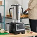 A large stainless steel commercial food blender with a digital control panel and dual handles.