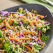 A bowl of salad featuring organic white quinoa mixed with shredded carrots, purple cabbage, and leafy greens.
