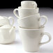 A stack of Tuxton Europa eggshell white espresso cups.