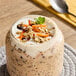 A jar of overnight oats topped with granola, shredded carrots, and a mint leaf.