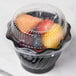 A clear dome lid on a plastic container filled with fruit.