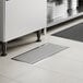 A 12-inch by 30-inch stainless steel floor trough with a grate, installed in a tiled floor.