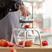 A man using a Vollrath vegetable dicer to cut a tomato.