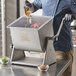 A person in gloves pouring food into a Backyard Pro meat mixer.