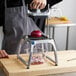 A person using a Vollrath vegetable dicer to cut onions into a glass container.