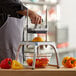 A person using a Vollrath vegetable slicer to cut yellow and orange bell peppers.