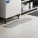 A 12 inch by 48 inch stainless steel floor water receptacle with a grate, designed for commercial kitchen use.