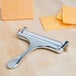 A Thunder Group aluminum cheese slicer with cheese on top of it.