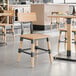 A Lancaster Table & Seating wooden chair with metal accents at a wooden table in a restaurant.