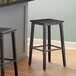 Two Lancaster Table & Seating Rustic Industrial Backless Bar Stools with Antique Slate Gray Finish on a wood floor next to a counter.