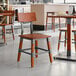 A Lancaster Table & Seating wooden chair with metal legs in a restaurant.