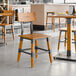 A Lancaster Table & Seating industrial chair with a honey maple finish and wooden seat.