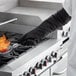 A person wearing SafeMitt oven mitts cooking food on a pan.