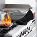 A person using a SafeMitt oven mitt to cook food on a stove.