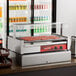 An Avantco pass-through canopy sneeze guard on a hot dog roller grill counter.