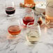 Acopa stemless wine glasses filled with white and red wine on a table in a winery.