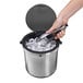 a hand holding tongs and ice cubes in a trash can