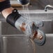 A person washing a SafeMitt oven mitt at a sink.