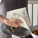 A person holding a Choice terry cloth over a pan of food.