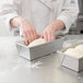 A person's hands kneading dough in a Chicago Metallic bread loaf pan.