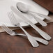 A Walco stainless steel salad fork on a plate with a knife and spoon.