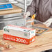 A woman using Choice Foodservice Film to wrap cookies on a table.