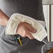 A person using a white terry cloth pan grabber with a Choice wrist slot to hold a pan.