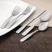 A white plate with silverware and Walco stainless steel dessert spoons on it.