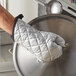 A hand holding a pot with a 13" silicone-coated oven mitt.