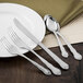 A white plate with silverware including a Walco Discretion serving spoon and fork on it.