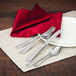 A table with a napkin and Walco stainless steel bouillon spoon and silverware on it.