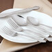 A white plate with a Walco Windswept stainless steel dessert spoon on it.