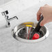 A hand using a Regency dipper well bowl to clean a sink.