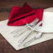 A table with a red napkin and Walco stainless steel table knife on it.