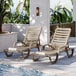 Two Grosfillex taupe resin chaise lounges on a patio.