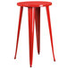 A red metal round table with two red metal stools.