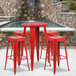 A Flash Furniture red metal bar height table with red square seat backless stools on an outdoor patio.