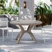 A Grosfillex round resin pedestal table with chairs on an outdoor patio.
