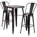 A Flash Furniture black metal table with a square top and two bar stools with square seats.