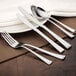 A white plate with a Walco Sonnet stainless steel salad fork on a placemat on a table.