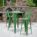 A Flash Furniture green metal bar height table with two green metal bar stools in front of a stone fireplace.