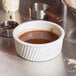 A Tuxton eggshell swirl ramekin filled with chocolate sauce on a table.