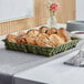 An American Metalcraft black square wire basket on a table with bread in it.