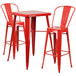 A red metal bar table with two red metal bar stools with backrests.