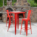 A red metal square bar height table with two red metal bar stools.