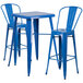 A blue metal bar table with a blue and white top and two blue metal stools.