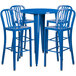 A blue metal round bar table with four blue metal bar stools.