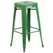 A green metal bar stool with a square seat.