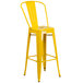 A yellow metal bar stool with a seat.